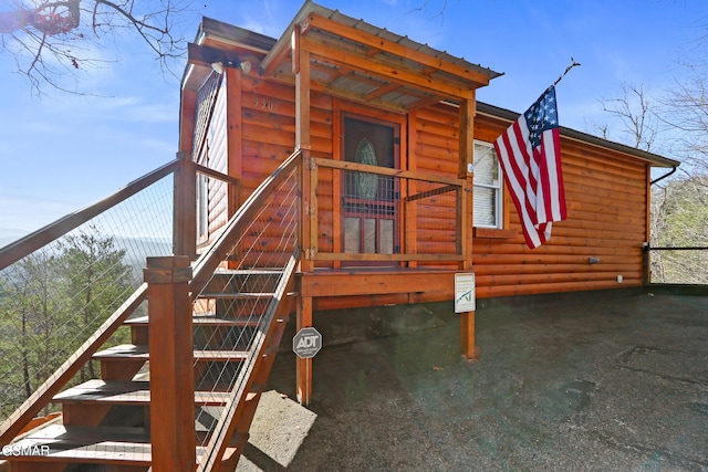 view of side of home featuring faux log siding and stairway