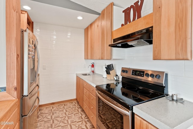 kitchen featuring light brown cabinets, under cabinet range hood, light countertops, appliances with stainless steel finishes, and light floors