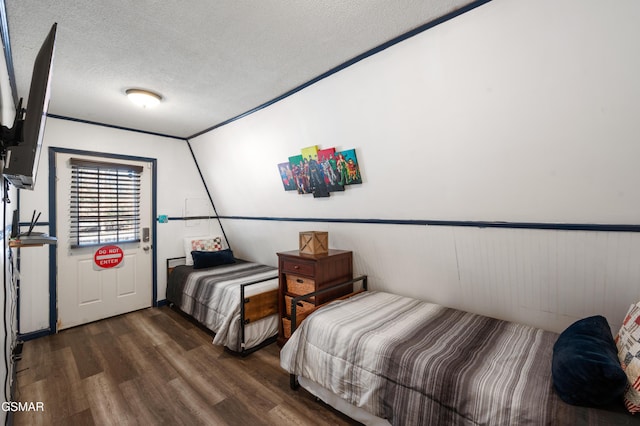 bedroom with a textured ceiling, dark hardwood / wood-style floors, and vaulted ceiling