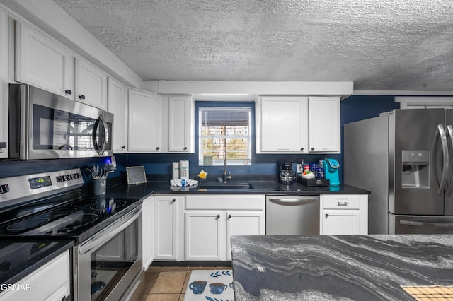 kitchen with white cabinets, a textured ceiling, appliances with stainless steel finishes, and sink