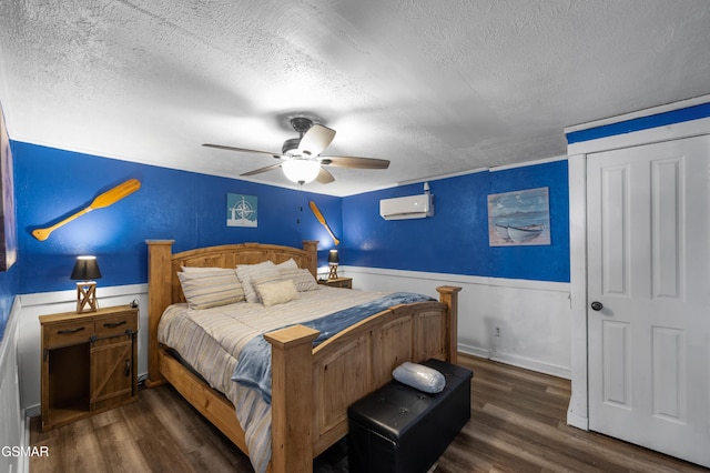 bedroom with a textured ceiling, a wall mounted air conditioner, ceiling fan, and dark hardwood / wood-style flooring