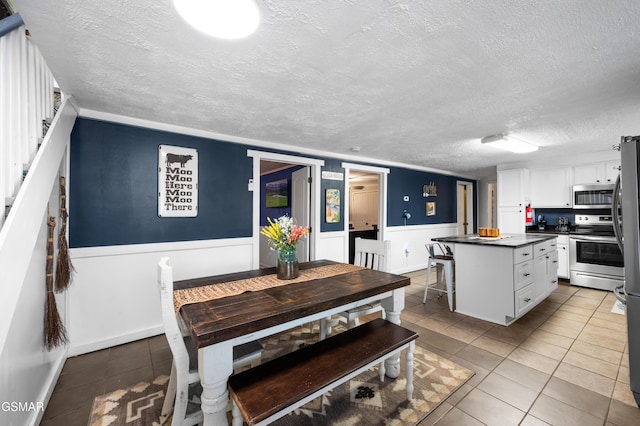 kitchen featuring white cabinets, a center island, light tile patterned floors, and appliances with stainless steel finishes