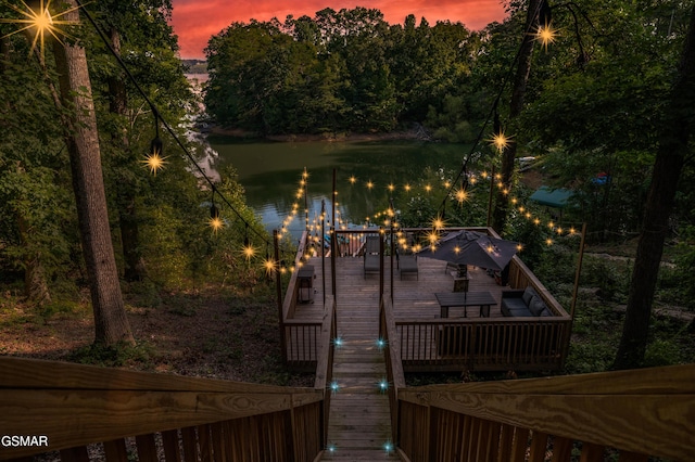 deck at dusk featuring a water view