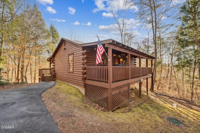 view of side of home featuring aphalt driveway and log exterior