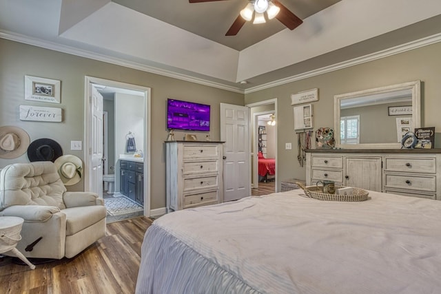 bedroom featuring a raised ceiling, connected bathroom, ceiling fan, ornamental molding, and wood-type flooring