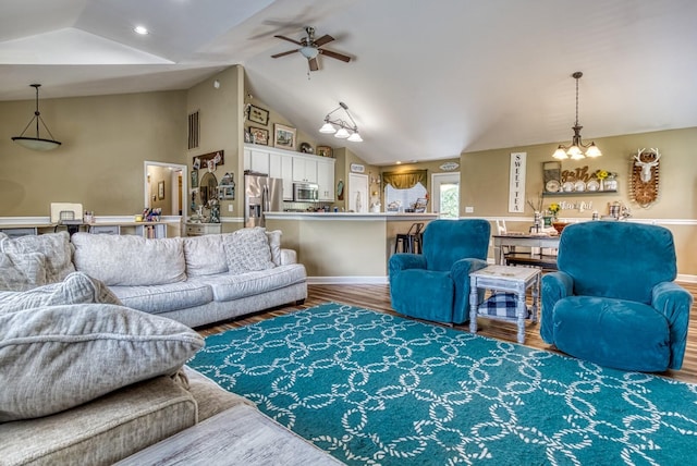 living room with lofted ceiling, ceiling fan with notable chandelier, and wood-type flooring