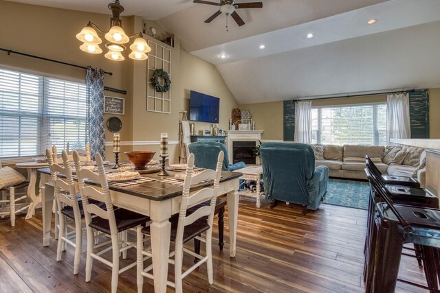 dining area with ceiling fan with notable chandelier, vaulted ceiling, and dark hardwood / wood-style floors