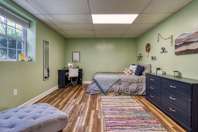 bedroom featuring a drop ceiling and wood-type flooring