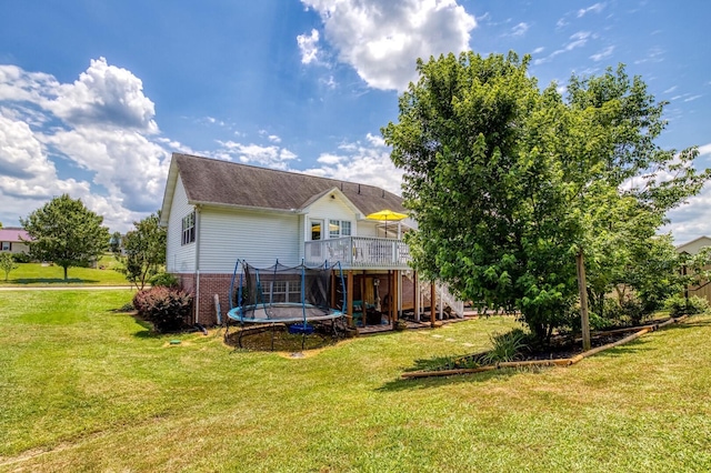 back of house with a yard, a deck, and a trampoline