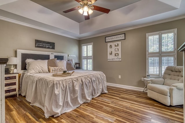 bedroom with ceiling fan, a tray ceiling, and hardwood / wood-style floors