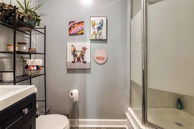 bathroom with toilet, an enclosed shower, and vanity