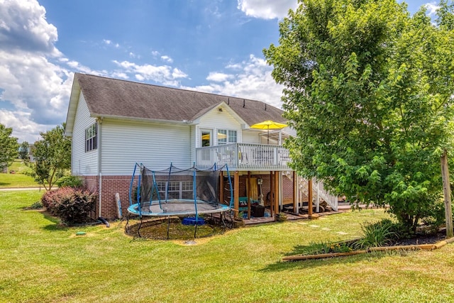 back of property featuring a lawn, a trampoline, and a wooden deck