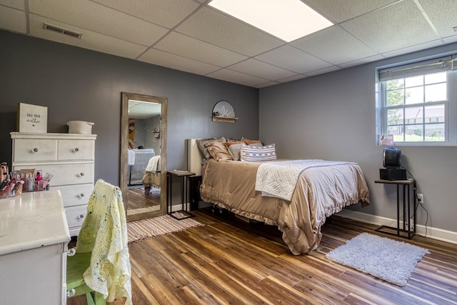 bedroom with dark hardwood / wood-style floors and a drop ceiling