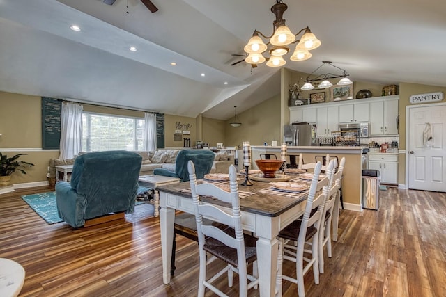 dining space with ceiling fan with notable chandelier, vaulted ceiling, and light hardwood / wood-style flooring