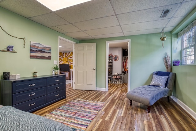 sitting room featuring dark wood-type flooring and a drop ceiling