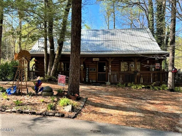 log home with log siding, covered porch, and metal roof