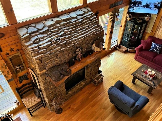 living room featuring a stone fireplace, wood finished floors, and visible vents