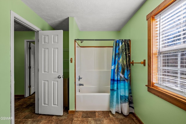 full bathroom featuring baseboards, a textured ceiling, stone finish floor, and shower / bath combination with curtain