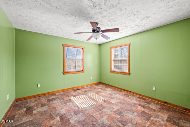 unfurnished room with ceiling fan, a textured ceiling, and baseboards