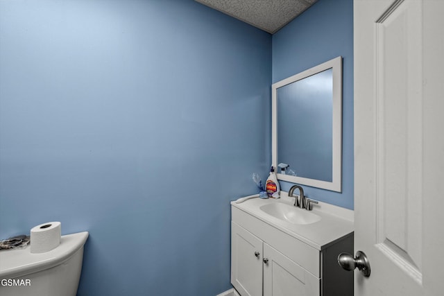 bathroom featuring toilet, vanity, and a textured ceiling