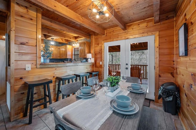 dining room featuring wood walls, french doors, wooden ceiling, and beam ceiling