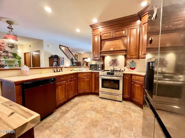 kitchen featuring custom exhaust hood, kitchen peninsula, appliances with stainless steel finishes, decorative light fixtures, and sink