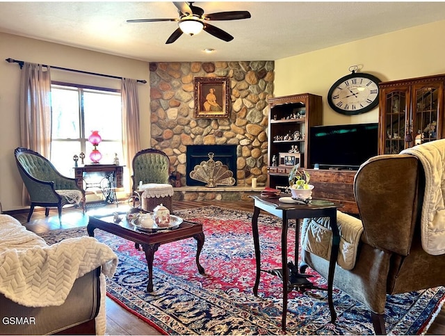 living room featuring ceiling fan, wood-type flooring, and a fireplace