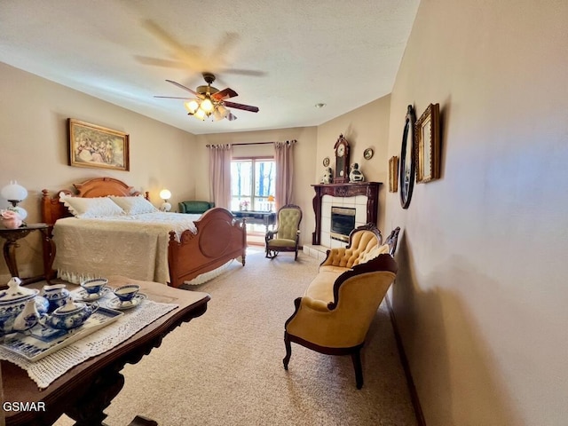 bedroom featuring ceiling fan, carpet, a tile fireplace, and a textured ceiling