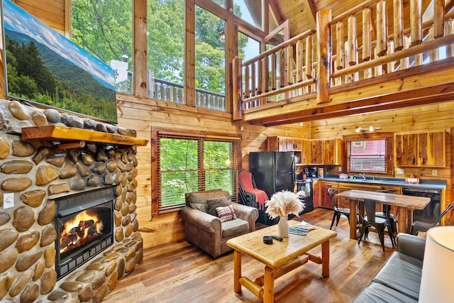 living room with high vaulted ceiling, light hardwood / wood-style flooring, and wood walls