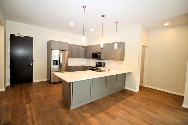 kitchen featuring gray cabinetry, a peninsula, light countertops, appliances with stainless steel finishes, and decorative backsplash