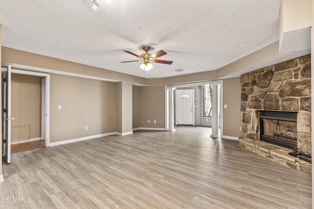 221 Woodland Rd Unit 315, Gatlinburg, TN 37738 - unfurnished living room with light wood-type flooring, baseboards, a textured ceiling, ceiling fan, and a fireplace