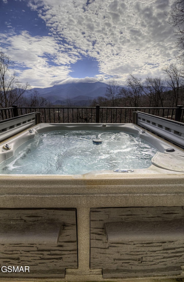 view of swimming pool with a mountain view and a hot tub