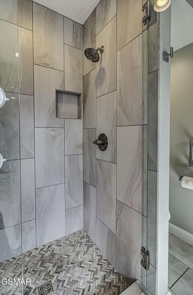 bathroom featuring a shower stall and baseboards