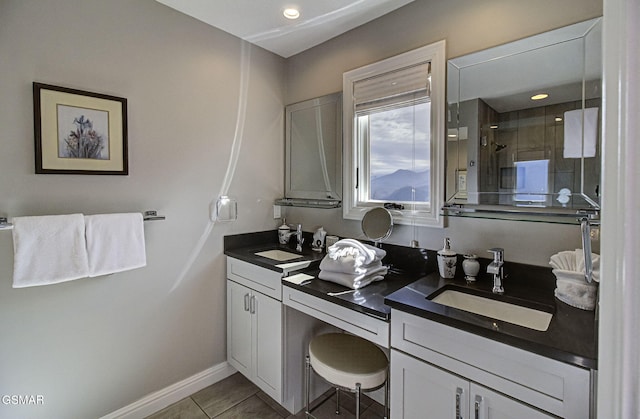 bathroom featuring tile patterned flooring, double vanity, a sink, and a stall shower