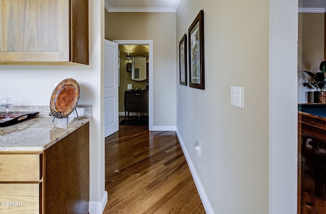 hall with crown molding, wood finished floors, and baseboards