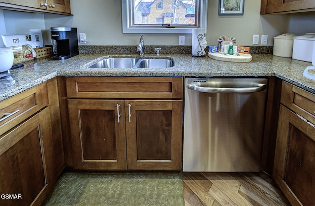 kitchen featuring stainless steel dishwasher, light stone countertops, and a sink