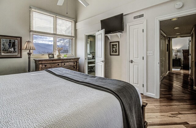 bedroom with ceiling fan, a towering ceiling, visible vents, wood finished floors, and baseboards