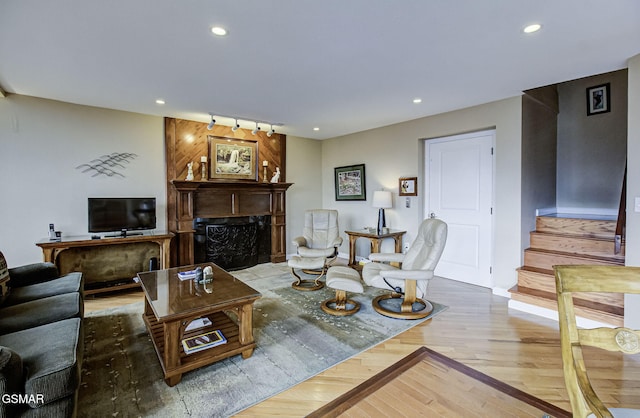 living room featuring a fireplace, rail lighting, recessed lighting, wood finished floors, and stairs