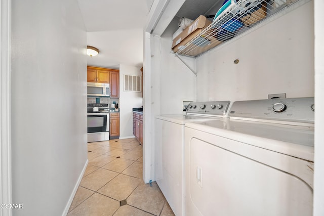 laundry area with light tile patterned floors and washing machine and clothes dryer