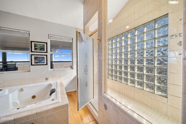 bathroom with plenty of natural light, independent shower and bath, vaulted ceiling, and a textured ceiling