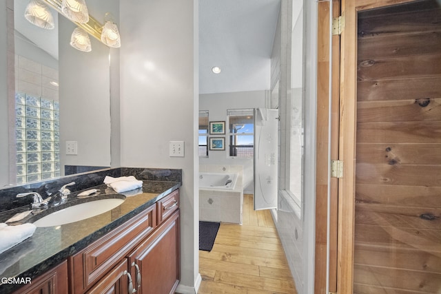 bathroom featuring hardwood / wood-style flooring, vanity, and plus walk in shower