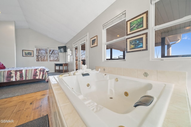 bathroom featuring tiled tub, plenty of natural light, and lofted ceiling