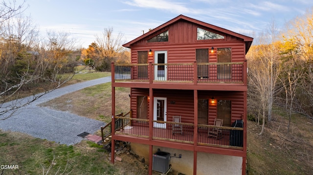 back of property with board and batten siding, central AC, and faux log siding