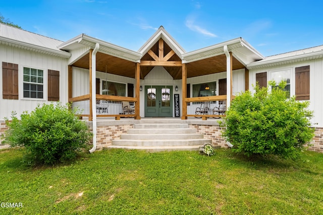 rear view of house featuring covered porch, a yard, and board and batten siding
