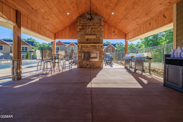 view of patio featuring an outdoor stone fireplace, fence, and a ceiling fan