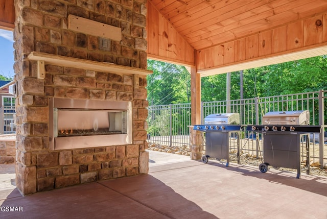 view of patio / terrace featuring fence, an outdoor stone fireplace, and area for grilling