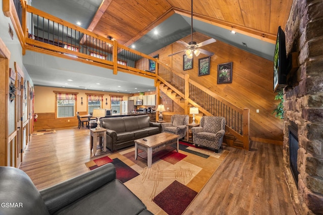 living area with wooden walls, wood ceiling, wood finished floors, stairs, and a fireplace