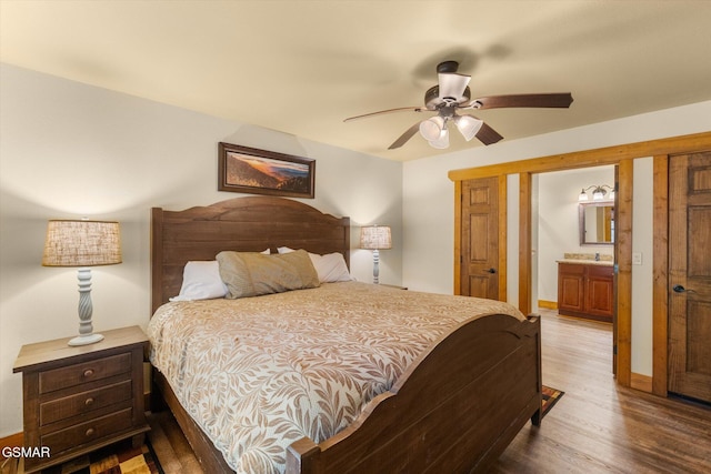 bedroom featuring ceiling fan, baseboards, wood finished floors, and ensuite bathroom