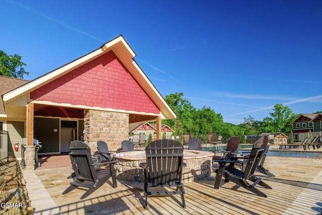 wooden deck with a fire pit and a patio