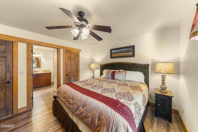 bedroom featuring ensuite bathroom, light wood-type flooring, a ceiling fan, and baseboards